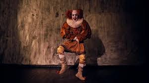 Scary clown with a crazy smile stands ...