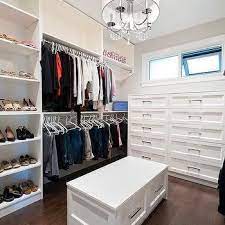 A white bench with shoe storage and a white and brown cushion sits on an antelope rug at hte side of a white closet island. Closet Design Decor Photos Pictures Ideas Inspiration Paint Colors And Remodel Closet Storage Design Closet Designs Closet Design