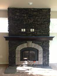 A beautiful stone fireplace made from stacked stone is a great way to create the perfect look for your living room. El Dorado Stone Stacked Stone Black River With Smoke Chiseled Edge Hearth Black Stone Fireplace Fireplace River Rock Fireplaces