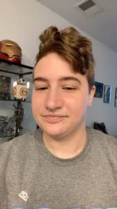 ID: Video of Ace talking to the camera. They flip the view and show a  cactus plant sticking out of a hand-made blue and green pot. The camera  pans to a budding calendula plant in a beige square pot. ...