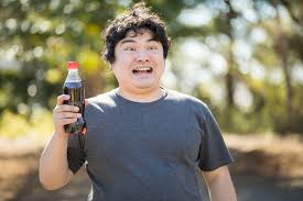 コーラ片手に不気味な笑みを浮かべる太っちょさんの写真｜フリー素材は「ぱくたそ」写真を無料ダウンロード