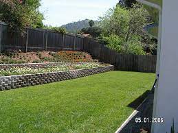 If you choose not to do this or need more of a wall structure for your slope, you may leave the lip on the stone and go for the tiered retaining wall design. Retaining Wall Slope Down To Flat Backyard Sloped Backyard Backyard Garden Landscape Sloped Garden