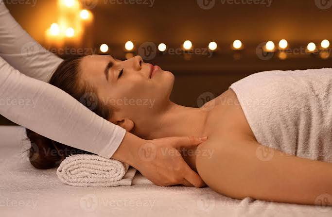 Peaceful young woman having relaxing full body massage at newest luxury spa decorated with candles. Female therapist rubbing sleeping lady shoulders, giving relaxing and body care session, side view 65938078 Stock Photo
