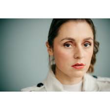 Zwischen Blau und Blick: Schauspielerin Lena Vogt vor einer klaren  Farbkulisse. Ihre Augen greifen das Blau der Wand auf