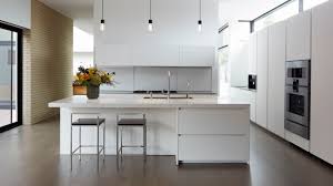 A minimalist kitchen with white cabinets, a top cabinet and open shelves, a stool and a printed rug. Minimalist Kitchens To Inspire You