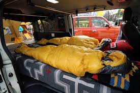 ハイエースの車中泊仕様 ライトキャンピングカーfd box 普段は普通の街乗りシートをフルフラットベッド展開 ナンガのシュラフで車中泊 東京アウト サイドフェスティバル 新宿中央公園 アウトドアイベント 出展車両 toyota hiace プラド 内装 ハイエース 車中泊