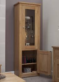 Showcasing decorative metal hardware, glass panels, and geometric trellis overlays, a pair of doors open to reveal shelves storage for china, barware, and table linens. Homestyle Gb Torino Chunky Oak Narrow Slim Glass Display Cabinet Oak Furniture Hut