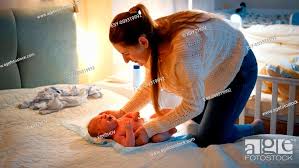 Young caring mother undressing her little baby and changing messy diapers  at night before going to..., Stock Photo, Picture And Low Budget Royalty  Free Image. Pic. ESY-059319992 | agefotostock