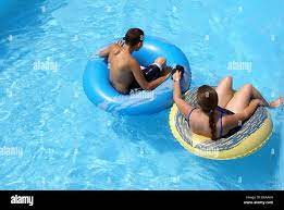 Mother and Son floating in Swimming Pool on inner tubes Stock Photo - Alamy