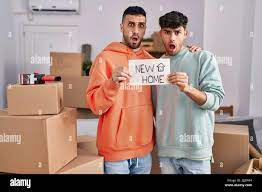 Young hispanic gay couple moving to a new home in shock face, looking  skeptical and sarcastic, surprised with open mouth Stock Photo - Alamy