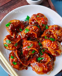 Schezwan Momos - Steamed momos tossed in spicy Schezwan sauce with vegetables on a white plate