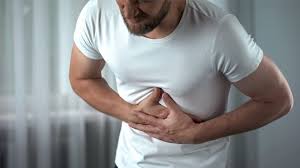 Person holding upper abdomen in discomfort, representing abdominal pain