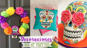 Un cartel negro con la frase día de los muertos y decoraciones en varios colores, dos centros de mesa con una calavera, y cuatro figuras con forma de calaveras con decoraciones de colores. Craftingeek