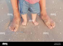 Mann und Baby Füße im flachen Wasser stehend Warten auf die Welle. Nackte  Füße Vater und seine kleine Tochter oder Sohn im Sand in der Nähe des  Meeres. Co Stockfotografie - Alamy