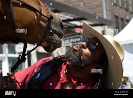 A member of the Federation of Black Cowboys NYC gives a kiss to his horse  Willow at the annual Target High Line Street Fair Stock Photo
