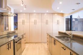White Uniform Flat Panel Glass Cabinets Line Up The Walls Of This Kitchen Floor To Ceiling Cabinets Cheap Kitchen Cabinets Birch Kitchen Cabinets