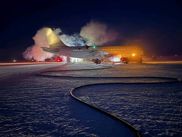 An aircraft landing on a snowy, dark airstrip in Antarctica during a specialized mid-winter medical evacuation mission.