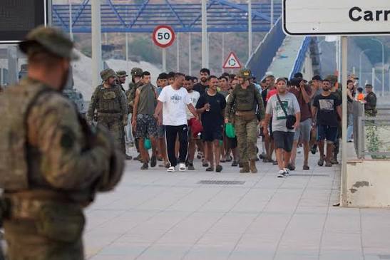 Migrants and security forces at the border fence of the Spanish North African enclave of Ceuta.
