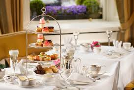 Elegant glass top dining room table setup with six place settings for a dinner party with white cloth napkins and wine goblets. 13 Best Places For Afternoon Tea In Dublin Right Now