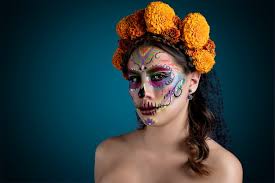 Mujer con maquillaje de Catrina y flores en el cabellos usando un vestido  blanco Dia de Muertos