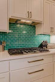 / the kitchen is the most important room in the house, we all know it and we all enjoy this happy thought, therefore we should all make the effort to improve it whether we only eat there or we spend hours and hours cooking. Modern White Kitchen With Bold Glass Tile Teal Backsplash Modernbacksplashblue Teal Kitchen Tile Ideas White Modern Kitchen Cheap Backsplash Tile
