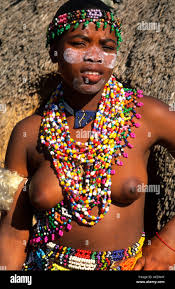 Zulu woman in beads and native costume topless near Kruger National Park in  South Africa near hut Stock Photo 