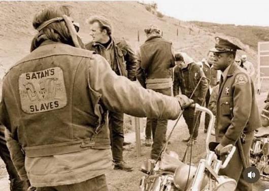 Satan's Slave Member Lewie Roseberry with his back to the camera, at a  roadblock. Used in the sixties to identify outlaw club members. Known as  Slave Lewie, he was a Satan Slave