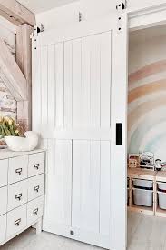 It is a hinged door that opens inward to provide access to the room when required. White Bedroom Design With White Wooden Door And Play Area For The Child