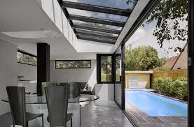 vranda avec verrire design donnant sur une terrasse avec piscine maison agrandissement maison maison contemporaine
