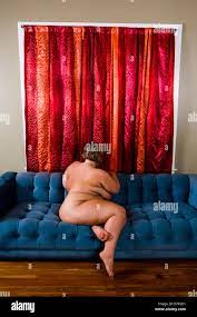 Nackte Frau sitzt auf der Couch im Wohnzimmer, Seitenansicht mit  Übergewicht Stockfotografie - Alamy