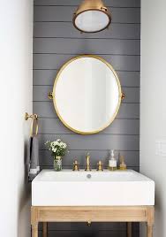 Small Stylish Powder Room Boasts An Oval Brass Pivot Mirror Mounted To A Dark Gray Shiplap B Powder Room Ideas Half Baths Powder Room Decor Powder Room Vanity