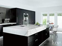 The backsplash made of white wood and white kitchen cabinets looks gorgeous with a dark wood floor and black hardware. 16 Kitchens With Marble Countertops That Wow Luxe Interiors Design