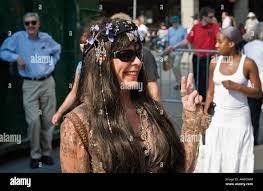 Attractive mature woman in hippie dress flashing a V peace sign dressed up  for 60 s music even Luminato festival Toronto Stock Photo 