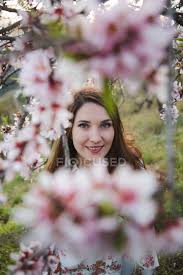 More images for lady fruit tree » View Through Twigs Of Blooming Fruit Tree Of Attractive Cheerful Lady Looking At Camera In Garden Nature Vertical Stock Photo 251670136