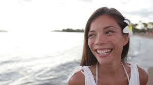 Beautiful beach woman portrait of happy girl looking at camera and to side  in white summer dress. Travel vacation holidays clip with multiracial Asian  girl, Waikoloa beach, Big Island, Hawaii, USA.