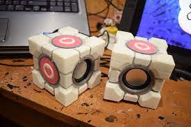It has a circular pink heart logo on each side of the cube. Portal 2 Companion Cube Audio Speaker Portal