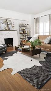 A Living Room Space With A Faux Cowhide Rug Art Nouveau Fireplace And Touches Of Gold Lazy Rugs In Living Room Cow Rug Living Room Layered Rugs Living Room