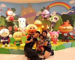child hugging a large Anpanman plush toy at the Fukuoka Anpanman Children's Museum in Mall.の画像
