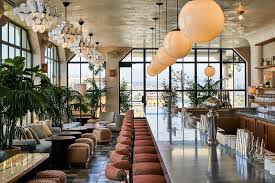A Long Shiny Bar With A Row Of Maroon Barstools Puffy Chairs And Coffeetables Are On The Furthest Wall Of The Bar At The End O Soho House Soho Courtyard Cafe