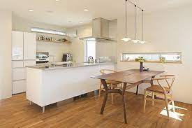 スタイリッシュなキッチンと濃色ブラックチェリーの床 テーブルが調和したオープンな対面キッチン 同色のブラックチャリーのダイニングテーブルとの相性は抜群です 壁には横に長い窓をつくりました そうすることにより テーブルに光が差し込み楽しい食卓に 専門家