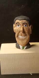 Whittling a wooden figure resembling Ronald Reagan