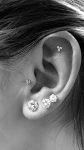 outer conch flat piercing paired with a tragus piercing and triple lobes raw crystal stud earrings earings piercings cool ear piercings