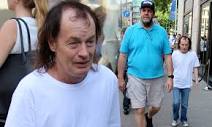 Angus Young, 60, is dwarfed by his bouncer as they stroll around ...