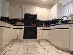 Compact kitchen with stainless steel countertops, four electric burners, oven, sink and refrigerator. White Or Grey Gloss Kitchen Can T Decide