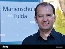 Fulda, Germany. 25th Feb, 2019. Teacher Peter Bach uses a document camera  to project a document onto a screen. On the wall there is a mobile phone  garage where the students deposit