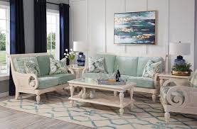 A white coastal living room with white furniture and curtains, a tan rug and a suspended ship. How Do I Decorate My Coastal Living Room The Pamaro Shop