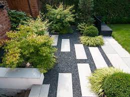 A grassy pathway is connected by stepping stones and looks alive and vibrant thanks to the beautiful and blooming tulips. What To Know About Installing A Walkway Of Pavers And Pebbles