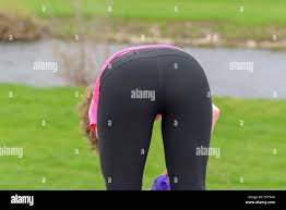 Sporty athletic woman bending over to remove her jacket while out jogging  alongside a rural river in a close up rear view conceptual of a healthy  acti Stock Photo - Alamy