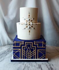 The gold filigree vines meanders upward from the gilded cake standand the blue vine twirls around. Wedding Cakes Alliance Bakery