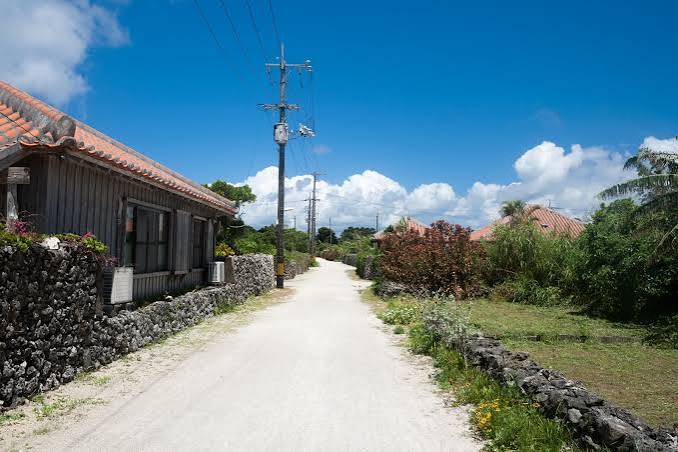 赤い屋根瓦と珊瑚の石垣に囲まれた竹富島の伝統的な民家の写真素材 - フリー素材ぱくたそ